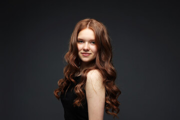 Naklejka premium Portrait of beautiful teenage girl with healthy wavy hair on dark grey background
