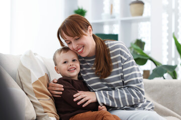 Happy mother spending time together with her son on sofa at home