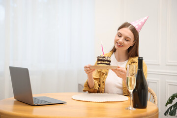 Birthday celebration. Happy woman with piece of cake having video call via laptop at home
