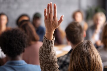 Engaged audience member raises hand during meeting, representing participation and active listening in group settings.