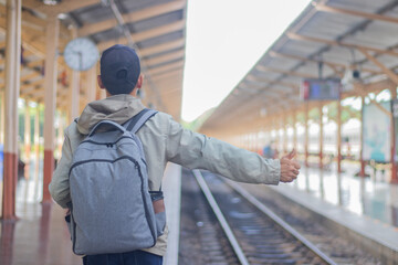 Confident young latin man standing alone at sunrise. Standing on train station platform, holding...