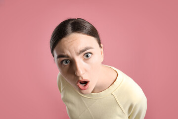 Portrait of shocked woman on pink background