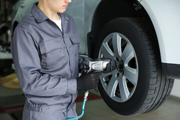 Mechanic changing tire at car service, closeup