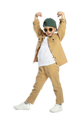 Cute little boy in sunglasses and baseball hat dancing on white background