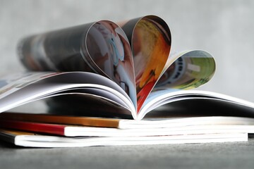 Stack of different magazines on grey table, closeup
