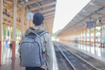 Confident young latin man standing alone at sunrise. Standing on train station platform, holding map. Confused but inspired. Travel, Direction, Exploring, Journey, Freedom, Lifestyle, Waiting, Serious
