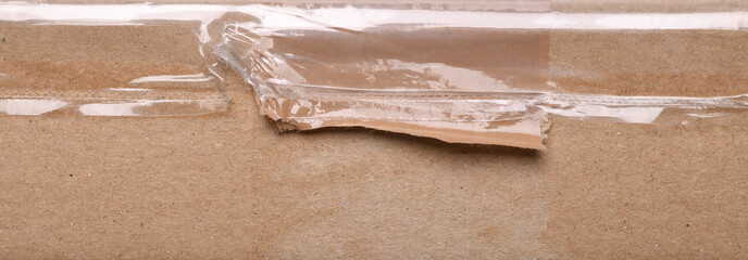 Surface of plain cardboard box with transparent plastic covering 