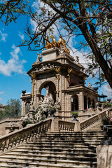 The ornate Cascada Monumental in Barcelona features elaborate sculptures and a golden chariot statue, viewed from the grand staircase below, Ciutadella Park