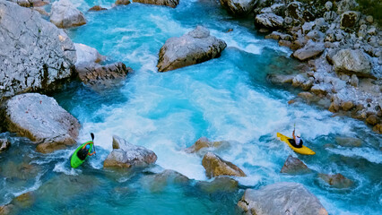 Two kayakers navigate turquoise rapids, captured from above, showcasing extreme adventure and nature's raw power.