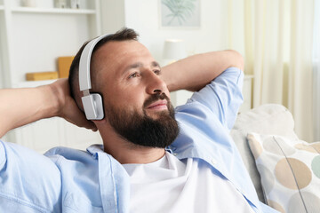 Obraz premium Harmony. Man listening to music in headphones on sofa at home