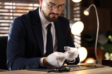 Appraiser with loupe evaluating ring at table indoors