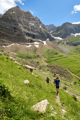 Fototapeta premium Hikers backpacking up a hill with mountains in the background.