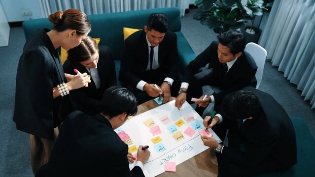 Top view of business people making scrum task board to manage workflow in workplace. Diverse marketing team drawing a line and use colorful stick notes to work on kanban. Creative office. Directorate.