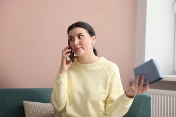 Young woman with bag complaining to customer service via phone at home