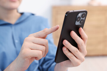 Woman using modern smartphone at home, closeup