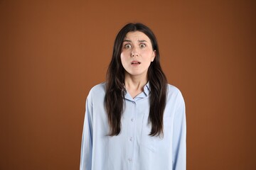 Portrait of shocked woman on brown background