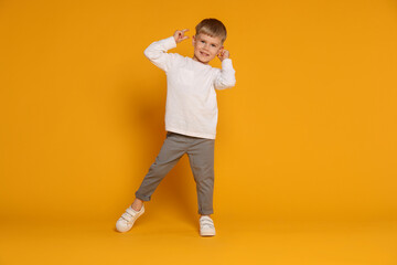 Happy little boy dancing on orange background
