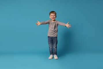 Happy little boy dancing on light blue background