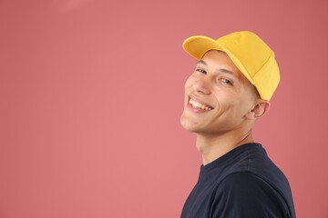 Young man in stylish baseball hat on pink background, space for text
