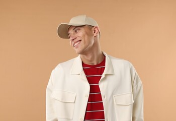Young man in stylish baseball hat on beige background