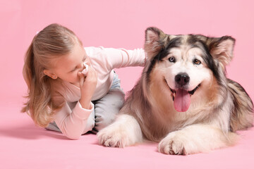 Girl suffering from allergy with her dog on pink background