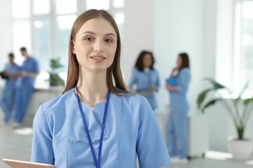 Medical student in uniform with tablet indoors, selective focus