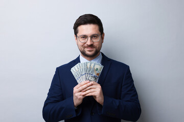 Greedy banker with dollar banknotes on grey background