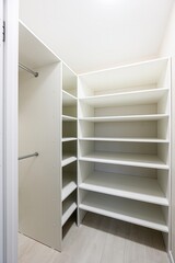 Clean, well-lit walk-in closet with white shelving and hanging rods. Organized and modern storage...
