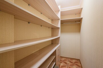 view of a walk-in closet with light wood shelving and a rod. The walls have a textured beige...