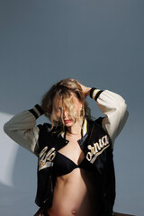 Beautiful pregnant young blonde in leather fashion jacket and panties with open belly stands on...