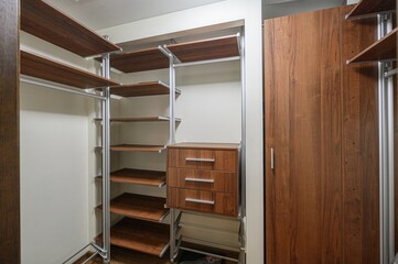well-organized closet featuring wooden shelves and drawers, and a wardrobe. The metal frames add a...