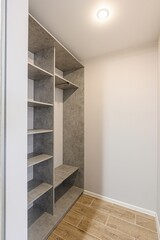 view into an empty closet with gray shelves and a hanging rod, set against a white wall and tiled...