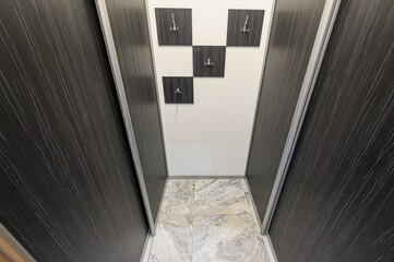 narrow hallway features dark, wood-textured sliding doors on either side, leading to a white wall...