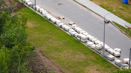 Stacks of paving slabs along sidewalk during urban infrastructure development, aerial view

