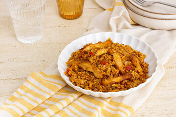 Plate of rice with chicken and vegetables on a table with glasses of water