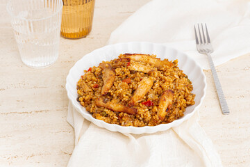 Plate of rice with chicken and vegetables on a table with glasses of water