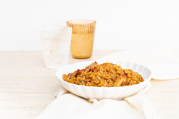 Plate of rice with chicken and vegetables on a table with glasses of water