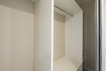 image shows a well-lit, partially open, white closet interior with a neutral-toned back wall. It...