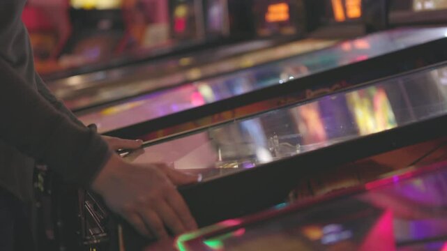 Person playing a pinball machine in arcade 4k