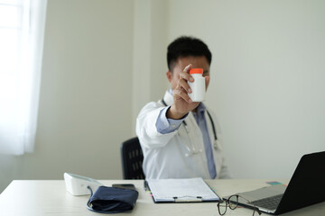 An asian young doctor is getting headache after duty and hand holding and rubbing hurt area,...