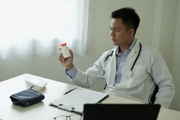 An asian young doctor is getting headache after duty and hand holding and rubbing hurt area,...