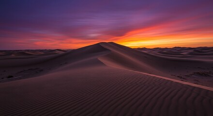 A dramatic, wide landscape of majestic sand dunes in a desert at sunset. The wind creates perfect ripples in the sand, and the sky is a fiery orange and purple.