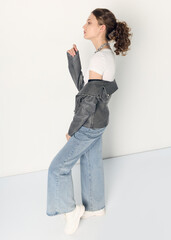 a woman dressed in accordance with fashion trends, in a leather jacket and a white top poses...