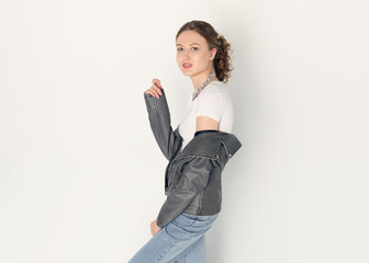 a woman dressed in accordance with fashion trends, in a leather jacket and a white top poses...