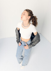 a woman dressed in accordance with fashion trends, in a leather jacket and a white top poses...