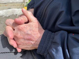 A close-up of an elderly man's wrinkled hands folded together