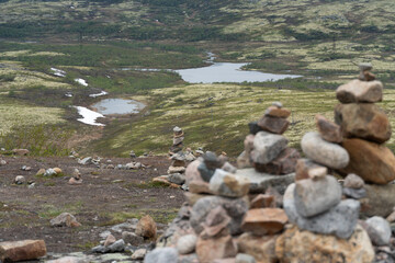 Stone cairns stacked on the tundra overlook a winding river and moss-covered hills near Teriberka,...