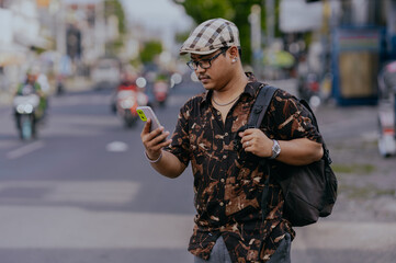 Asian man traveler in backpack using mobile phone while standing explore on the city street. Travel...