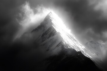Dramatic black and white mountain peak illuminated by sunlight through clouds
