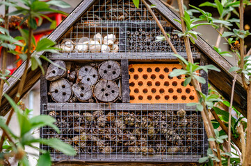 Insect hotel showcasing diverse materials for shelter in a lush garden setting during daylight hours